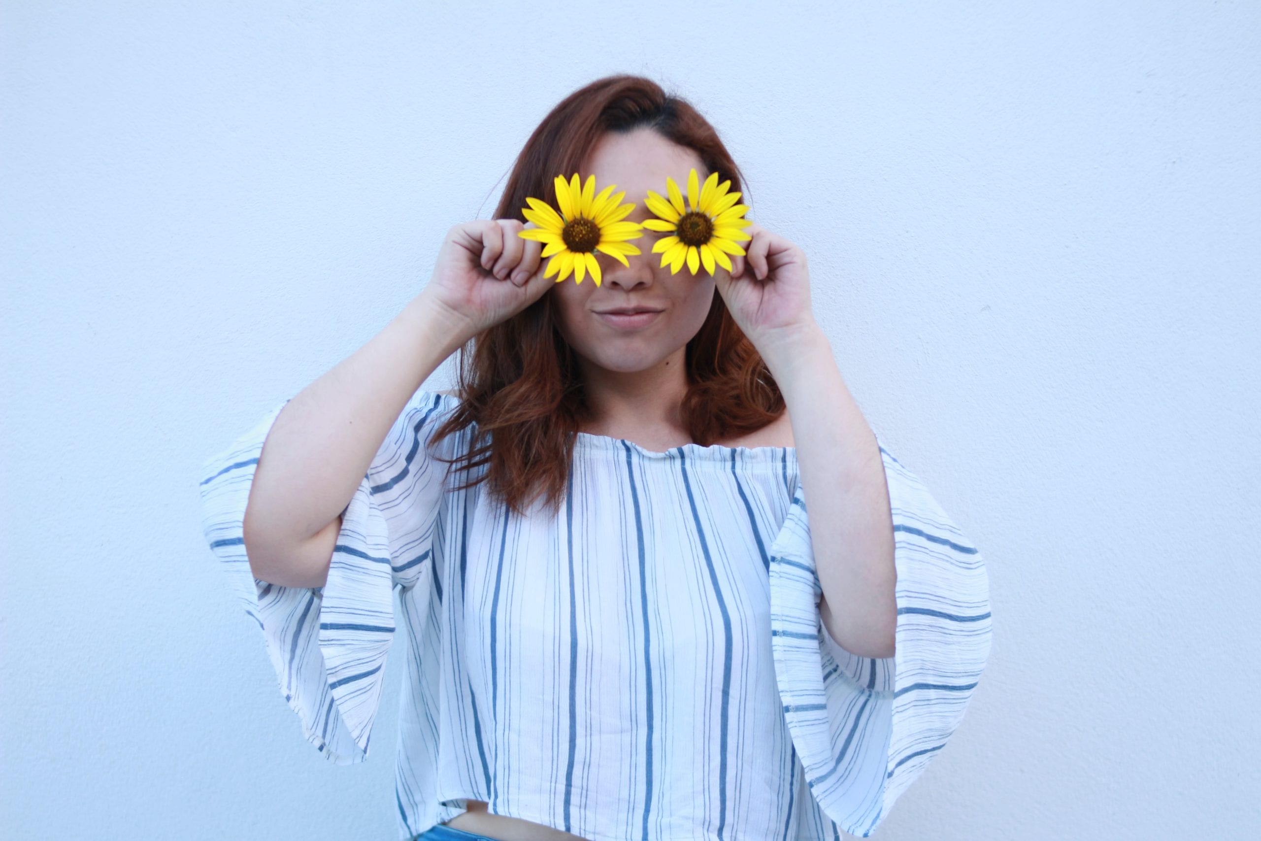 Girl holding sunflowers over her eyes