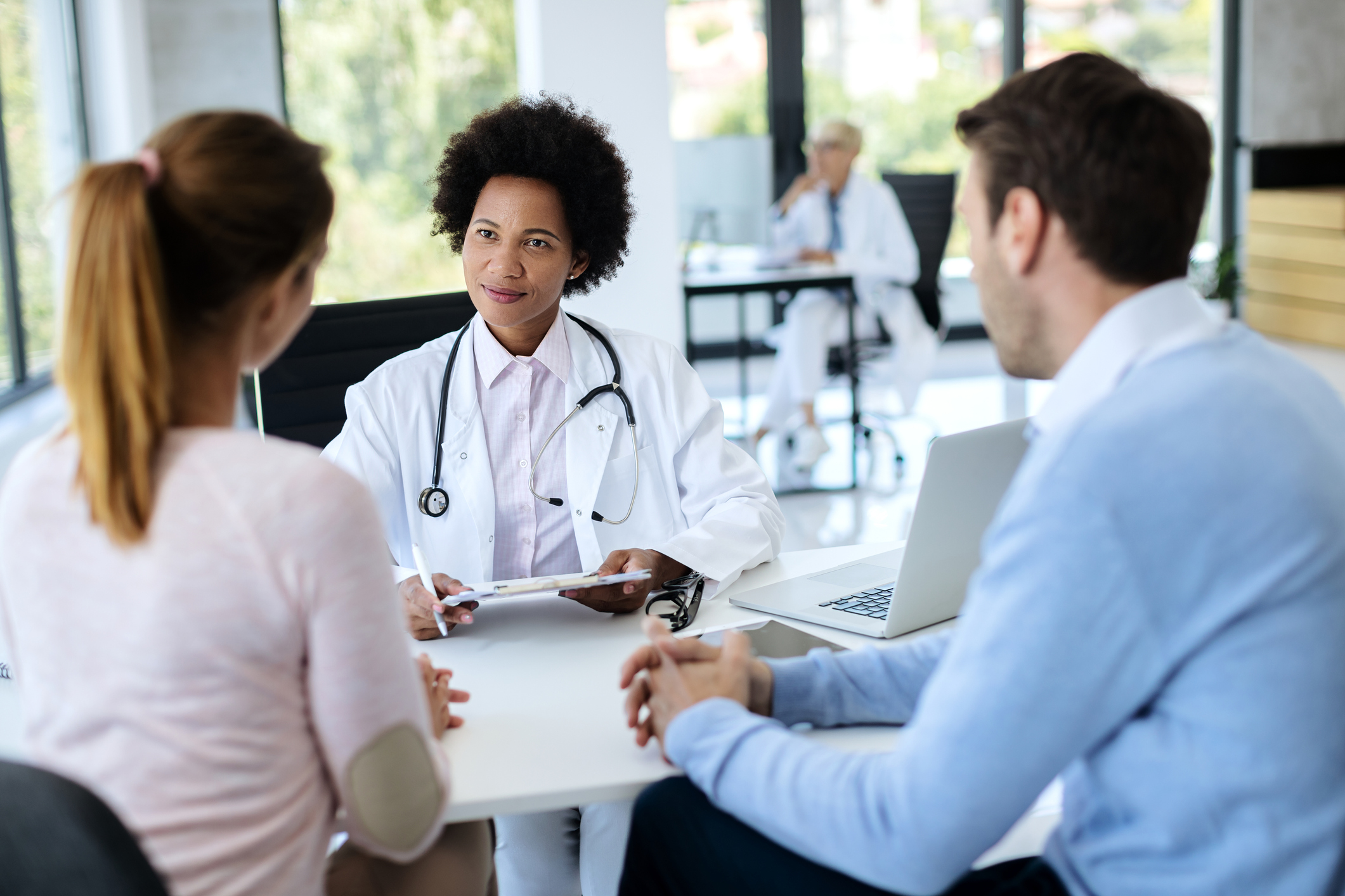 Black female doctor talking to a couple during medical counseling in the hospital.